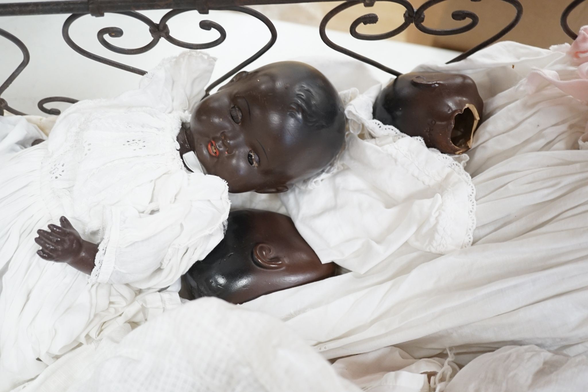 3 Armand Marseille bisque head dolls with sleeping eyes and 4 others in a wrought iron dolls crib 80cm